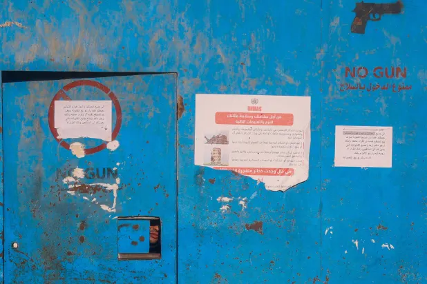 رجل يطل يوم الثلاثاء من فتحة في بوابة مركز توزيع تابع لوكالة (أونروا) في مخيم النصيرات بغزة (أ.ف.ب)