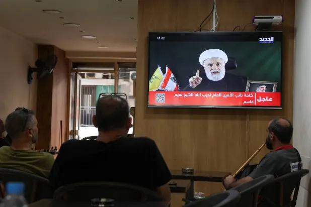 Lebanese in Beirut watch Naim Qassem deliver a speech. (Reuters)