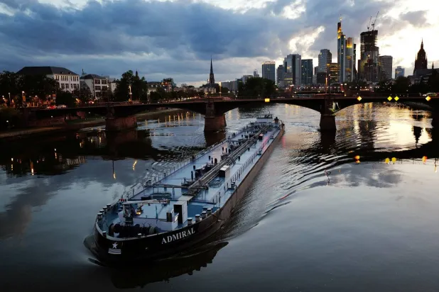سفينة شحن في نهر ماين أمام أفق مدينة فرنكفورت الألمانية (رويترز)