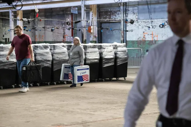 يقوم موظفان من مقاطعة أليغيني بإعادة صناديق الاقتراع من مواقع الاقتراع عبر الأقمار الاصطناعية إلى مستودع انتخابات مقاطعة أليغيني قبل يوم الانتخابات في بيتسبرغ ببنسلفانيا (أ.ف.ب)