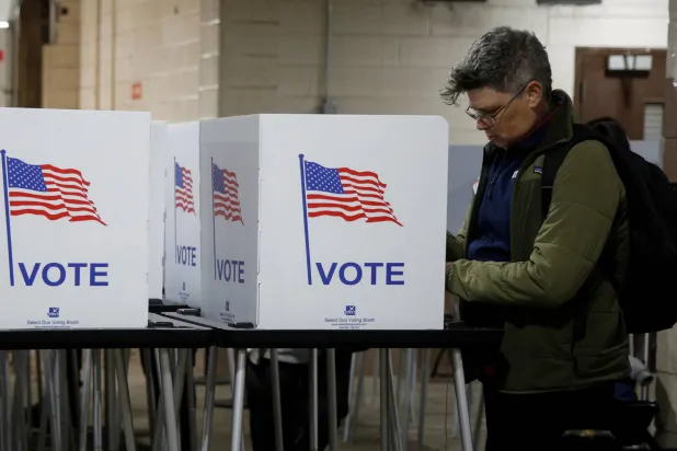 ناخب يدلي بصوته في الانتخابات الرئاسية الأميركية خلال عملية التصويت المبكر في ميشيغان (رويترز)