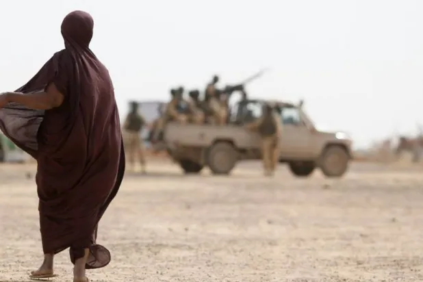 سيدة في إحدى قرى بوركينا فاسو تراقب آلية عسكرية تابعة للجيش (غيتي)