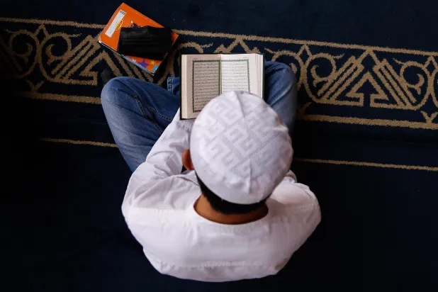 رجل يقرأ القرآن الكريم داخل الجامع الأزهر في القاهرة (غيتي)