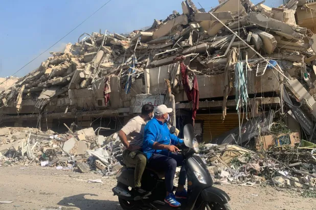 Beyrut'un güney banliyösü Haret Hreik'te İsrail bombardımanında yıkılan binaların önünden geçen iki Lübnanlı (AFP)