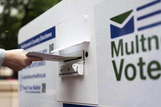 ناخب يُسقط بطاقة اقتراع بالبريد في أحد الصناديق أثناء التصويت في الانتخابات التمهيدية للرئاسة الأميركية (أ.ب)