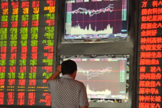 متداول يتابع حركة الأسهم في البورصة الصينية على شاشة بالعاصمة بكين (أ.ف.ب)