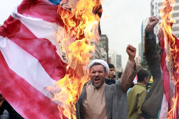 رجل دين إيراني يردد هتافات وسط حرق العلم الأميركي في تظاهرة ذكرى اقتحام سفارة واشنطن لدى طهران (إ.ب.أ)