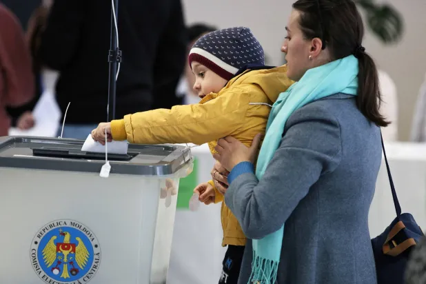 سيدة وطفلتها خلال الإدلاء بصوتها في مركز اقتراع خلال الجولة الثانية من الانتخابات الرئاسية بكيشيناو (رويترز)