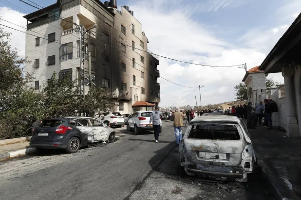 فلسطينيون يتفقدون مركباتهم المحترقة في موقع هجوم المستوطنين الإسرائيليين بالبيرة بالقرب من مدينة رام الله بالضفة الغربية (إ.ب.أ)