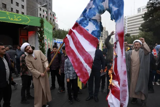 رجال دين يحرقون علم أميركا أمام مقر سفارتها السابقة في طهران (أ.ب)