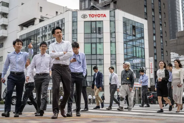 مشاة يمرون أمام مقر شركة «تويوتا» لصناعة السيارات في العاصمة اليابانية طوكيو (أ.ف.ب)