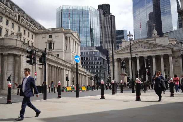 أشخاص يسيرون أمام بنك إنجلترا في الحي المالي في لندن (إيه بي أي)
