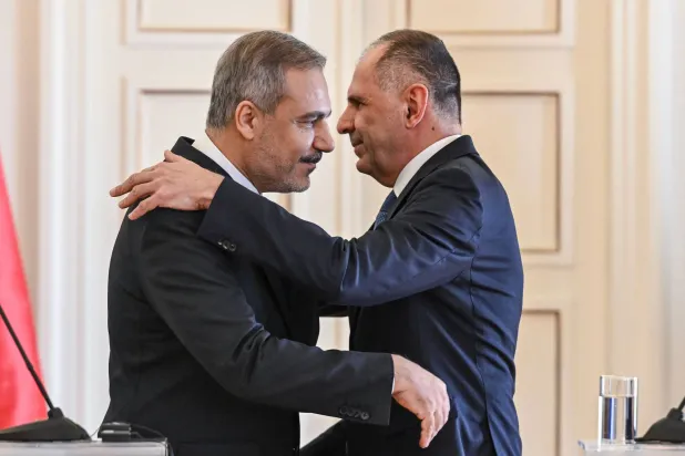 وزير الخارجية التركي هاكان فيدان (يسار) ونظيره اليوناني جورج جيرابتريتيس يختتمان المؤتمر الصحافي في أثينا بعناق نادر (أ.ف.ب)