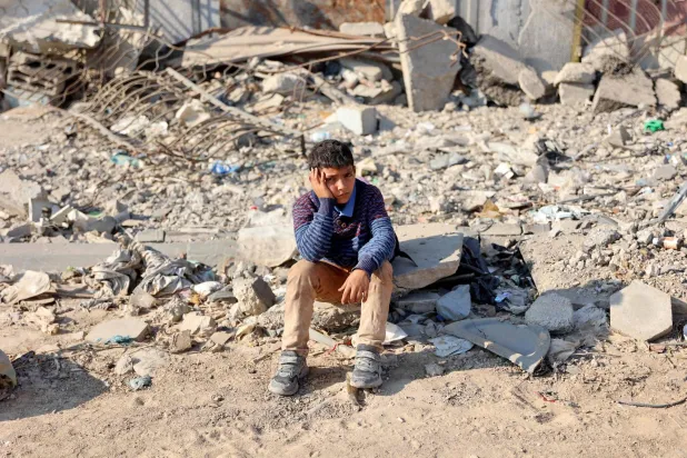 فتى فلسطيني نازح من شمال قطاع غزة يجلس على أنقاض منزل مهدم على مشارف مدينة غزة (أ.ف.ب)