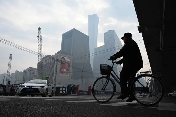 رجل على دراجة بأحد شوارع الضاحية المالية بالعاصمة الصينية بكين (أ.ف.ب)