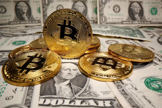 عملات بتكوين على أوراق نقدية من الدولار الأميركي (رويترز)