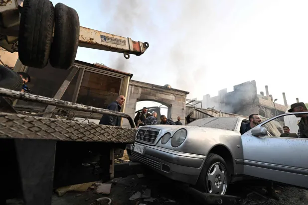 سوريون يعاينون الأضرار التي خلفتها الغارة الإسرائيلية على حي المزة بدمشق الخميس (أ.ف.ب)