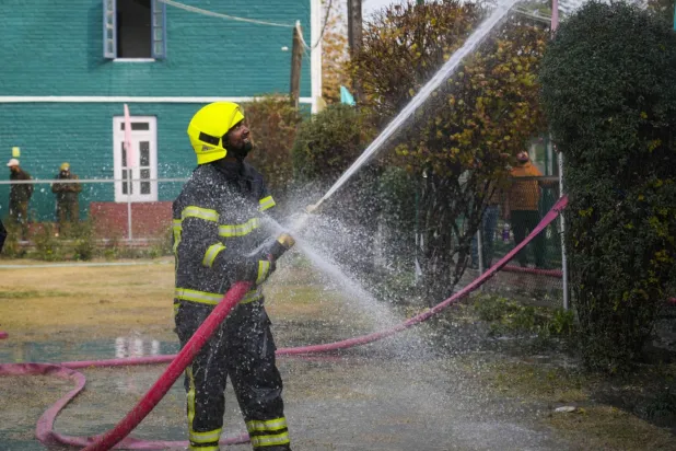 Hindistan’da bir okulda çıkan yangını söndürmeye çalışan itfaiyeci (AP)