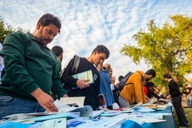 عراقيون يعاينون كتباً معروضة بشارع أبو نواس وسط بغداد ضمن فعالية «أنا عراقي أنا أقرأ» حيث وزع 30 ألف كتاب مجاناً (أ.ف.ب)