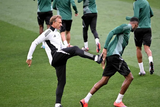 مدرب الأخضر يمازح محمد كنو خلال التدريبات (أ.ف.ب)