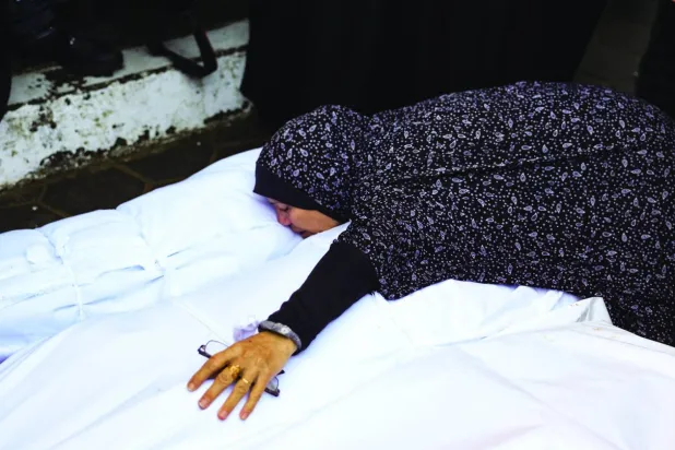 Filistinli bir kadın dün Gazze'nin merkezindeki El Aksa Şehitleri Hastanesi'nde İsrail hava saldırısında ölenlere veda etti (AFP)