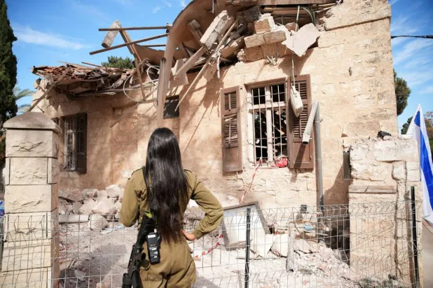 An Israeli soldier stands next to a building hit by missiles fired by Hezbollah in Haifa (Reuters)