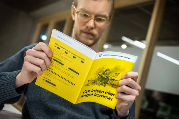 رجل مع نسخة 2024 من كتيب «في حالة الأزمات أو الحرب» في استوكهولم