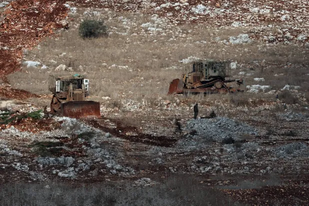 جنديان إسرائيليان وسط جرافتين في بلدة مارون الراس بجنوب لبنان (إ.ب.أ)