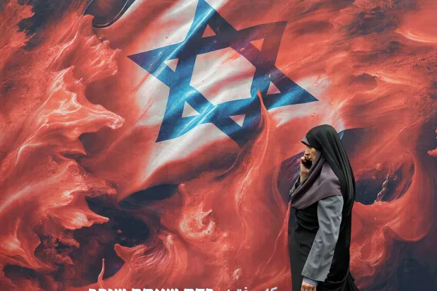 إيرانية تمرّ أمام لوحة إعلانية مناهضة لإسرائيل كُتب عليها بالعبرية: «في الدم الذي سفكتَه ستغرق» (إ.ب.أ)
