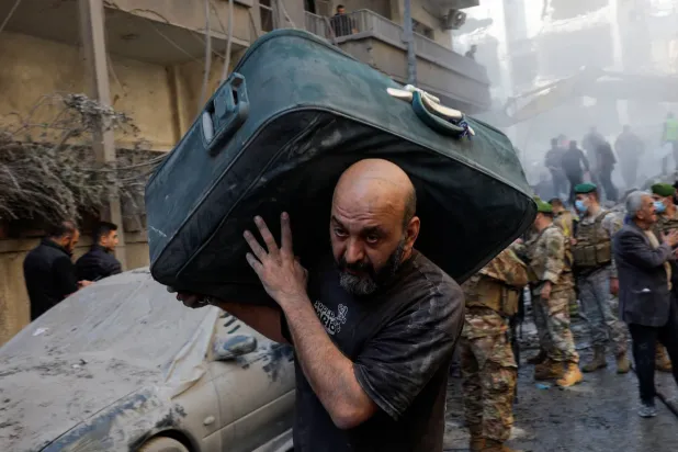 شهروند لبنانی در حال ترک منطقه بسطا در بیروت پس از حمله هوایی اسرائیل (رویترز)