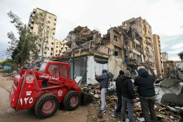 Beyrut'un güney banliyölerindeki eş-Şayıh mahallesini hedef alan İsrail hava saldırısının gerçekleştiği yerde yıkımı inceleyen insanlar (AFP)