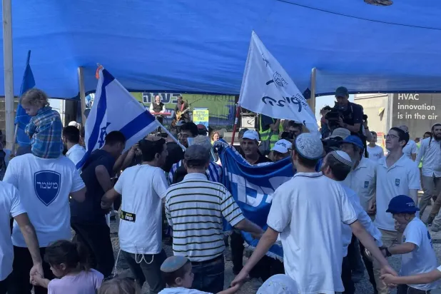 Settler activists dance at a conference calling for the establishment of Jewish settlements in Gaza, close to the Israel-Gaza border, October 21, 2024. (Jeremy Sharon/Times of Israel)