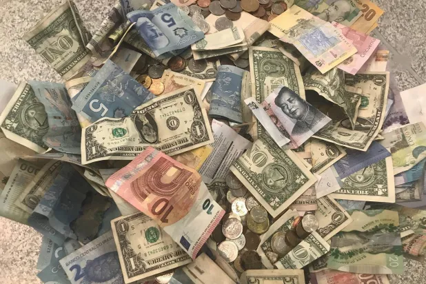 دولارات أميركية وعملات أخرى في صندوق تبرعات بمطار بيرسون الدولي بتورنتو (رويترز)