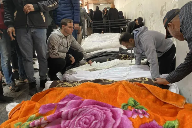 فلسطينيون يبكون أمام جثث أقاربهم الذين قُتلوا في الغارات الإسرائيلية بمستشفى الأهلي العربي (المعمداني) بغزة قبل تشييع جنازتهم (د.ب.أ)