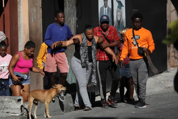 تتلقى امرأة المساعدة عندما أحرق مدنيون غاضبون جثث أفراد عصابة مشتبه بهم في هايتي (رويترز)