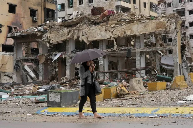 A Lebanese woman passes by the rubble of a building in Beirut's southern suburbs (Reuters)