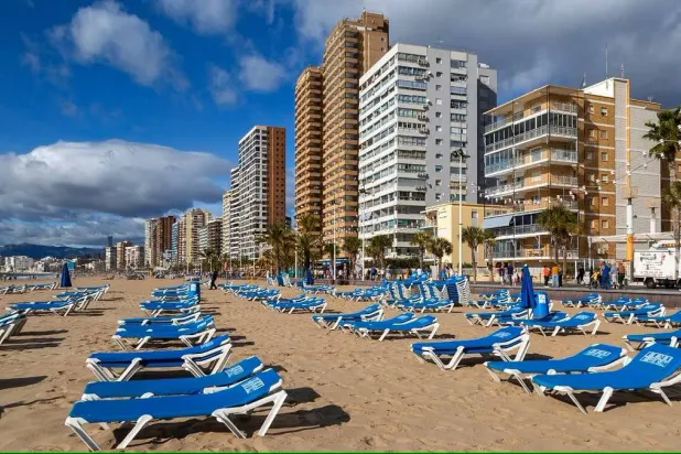 فنادق وكراسي الاستلقاء للتشمس بالقرب من شاطئ في بينيدورم بإسبانيا (شاتيرستوك)