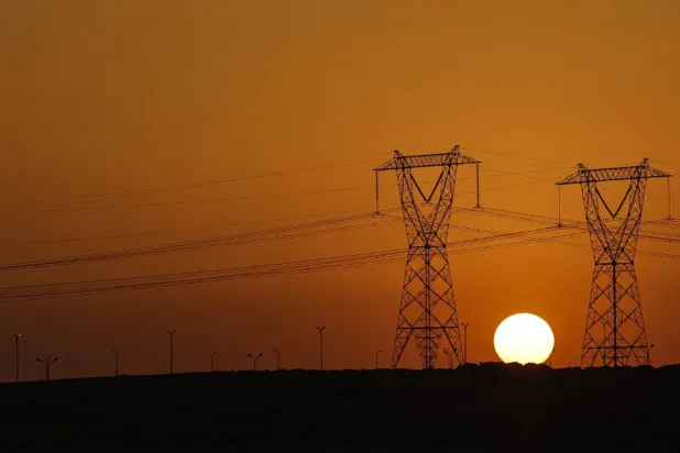 غروب الشمس بين أبراج الضغط العالي للكهرباء (رويترز)