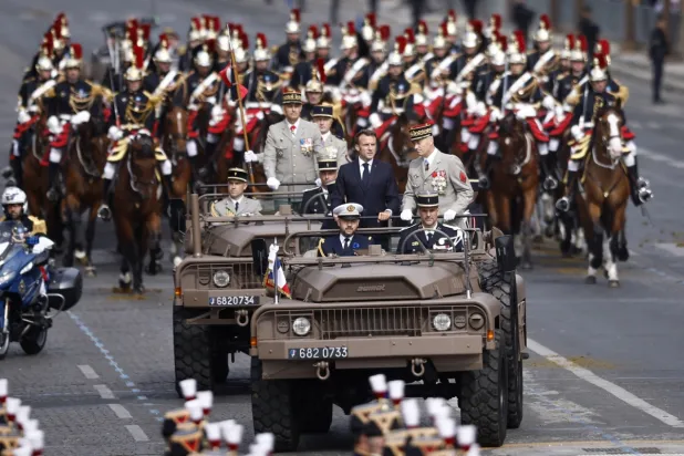 Fransa Cumhurbaşkanı Emmanuel Macron ve Genelkurmay Başkanı Thierry Burkhard, yıllık askeri geçit töreni sırasında Şanzelize Caddesi’ne gelirken (EPA)