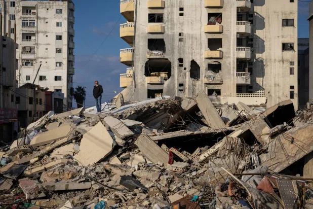 مواطن يقف على أنقاض منزله المُدمَّر في صور بجنوب لبنان (رويترز)