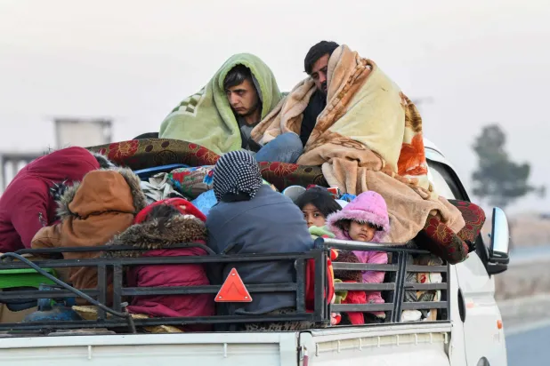 نازحون أكراد سوريون على مركبات محملة بالأمتعة على طريق الرقة السريع أثناء نزوحهم من مناطق بمدينة حلب باتفاق بين القوات الكردية والفصائل (أ.ف.ب)