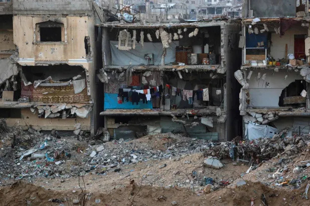 تظهر الصورة ملابس معلقة لتجف على حبل في مبنى متضرر بشدة في حي مدمر بسبب الغارات الإسرائيلية في جنوب قطاع غزة (أ.ف.ب)