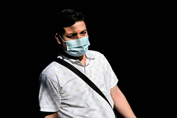 رجل يرتدي قناعاً واقياً في دلهي بالهند (أ.ف.ب)