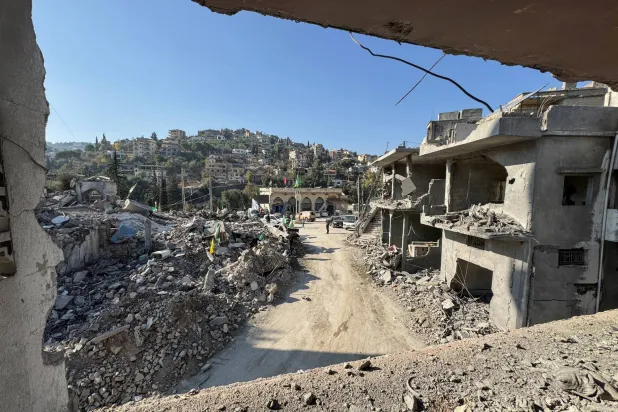 أشخاص يقفون قرب مبانٍ متضررة في خربة سلم بعد وقف إطلاق النار بين إسرائيل و«حزب الله» جنوب لبنان اليوم (رويترز)