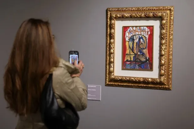 A woman takes pictures of an illustration for Romeo and Juliet by Salvador Dali at exhibition "SalvArti, from Confiscations to Public Collections", a showcase of contemporary artworks coming from confiscations carried out by public authorities against organized crime, in Milan, Italy, December 3, 2024. (Reuters) 