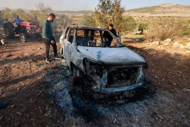 رجال يتفقدون سيارة محترقة قيل إنها تعرضت لغارة جوية إسرائيلية في قرية العقبة الفلسطينية بالقرب من مدينة جنين بالضفة الغربية 3 ديسمبر 2024 (أ.ف.ب)
