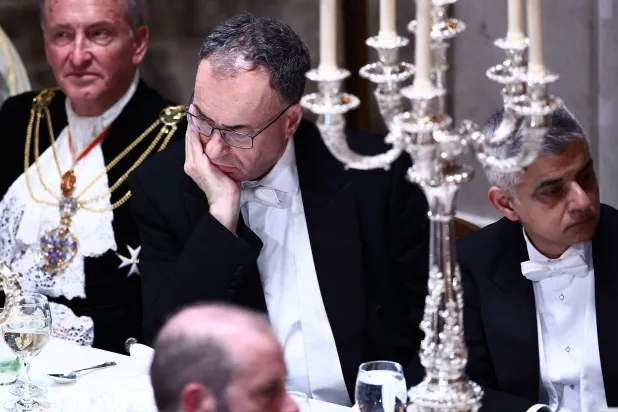 محافظ بنك إنجلترا (وسط) يستمع لرئيس الوزراء البريطاني ستارمر وهو يلقي خطاباً خلال مأدبة اللورد مايور بقاعة غيلدهول وسط لندن (أ.ف.ب)