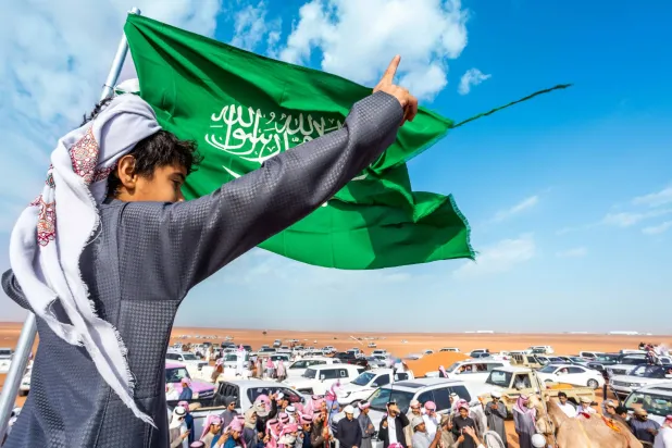 أحد الشبان يلوح بالعلم السعودي للمشاركين في المهرجان (الشرق الأوسط)