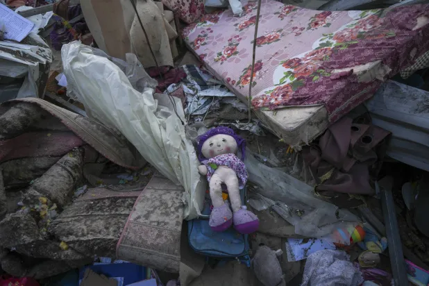 A doll lies among plastic debris and clothes in the aftermath of an Israeli airstrike at the Muwassi camp near Khan Younis, in the southern Gaza Strip, on Thursday, Dec. 5, 2024. (AP Photo/Abdel Kareem Hana)