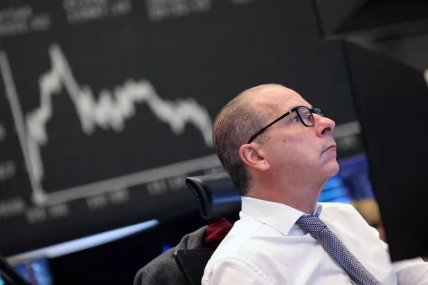 متداول أمام رسم بياني يعرض مؤشر «داكس» في بورصة فرانكفورت (أ.ف.ب)